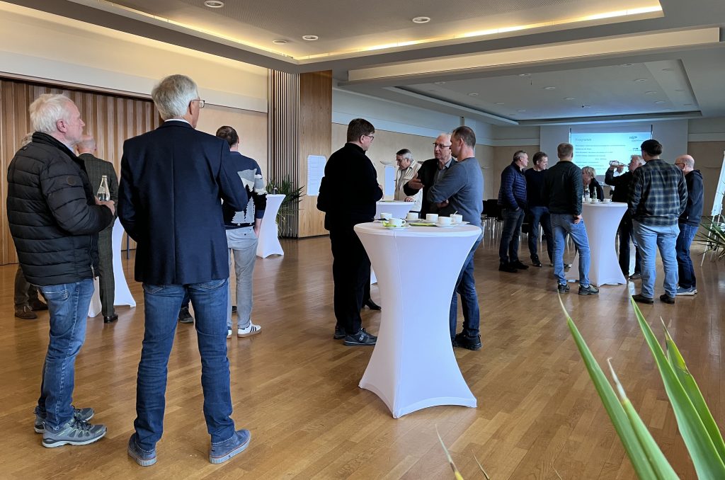 Die Teilnehmer des Unternehmerdialogs stehen in Grüppchen zusammen und unterhalten sich.